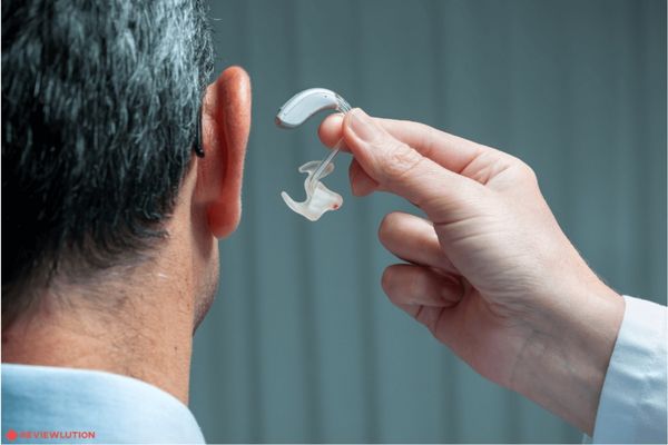 A Doctor putting on an hearing aid to a person
